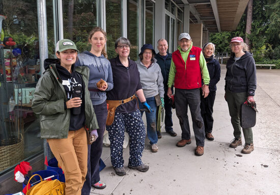 Eight Habitats at Home installation team members standing outside Bellevue Botanical Garden in work clothes, some holding garden tools.